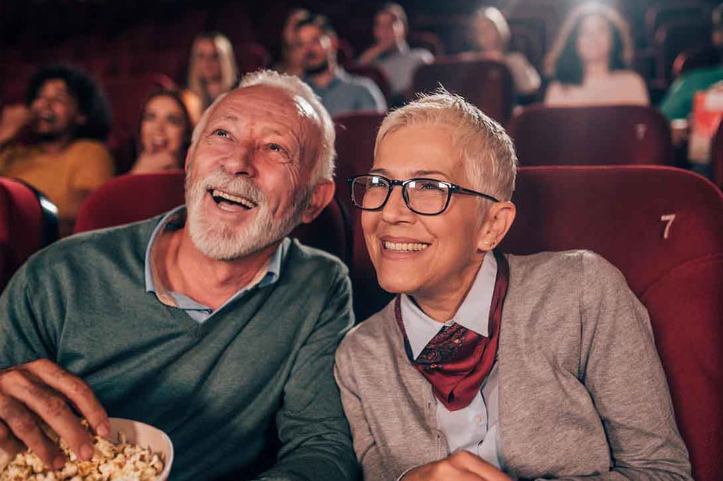 Laiminga yresnio amžiaus pora žiūri filmą kino teatre