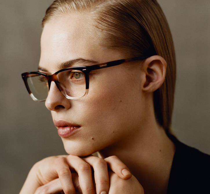 Moteris su rudais plastikiniais Calvin Klein akiniais.